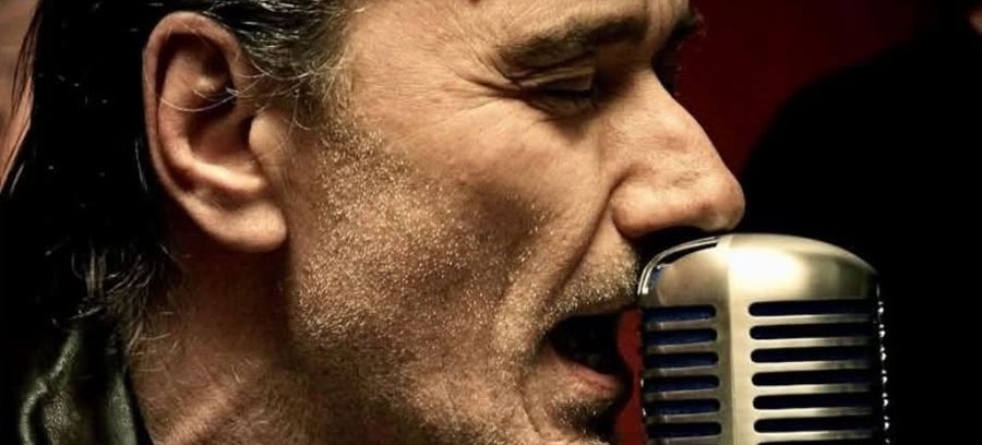 Carlo Casale che canta davanti a un microfono d'epoca