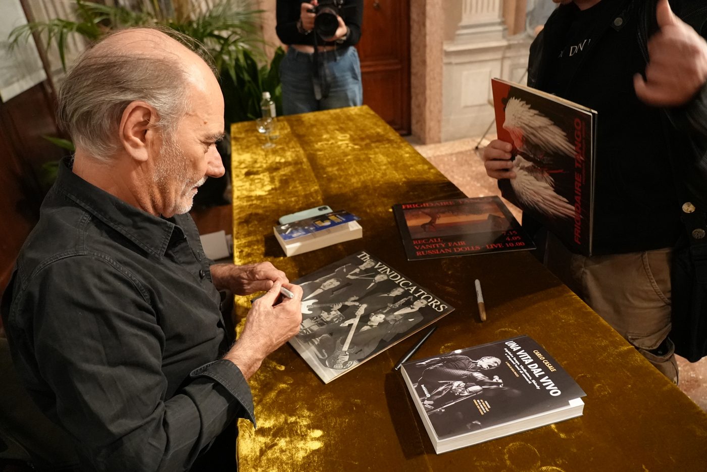 Carlo Casale signing a record at Libreria Palazzo Roberti, with his book on the table